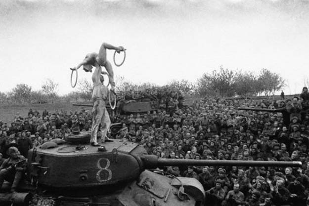 Soviet soldiers take a break to watch an acrobatic show on the march towards Berlin (1945)