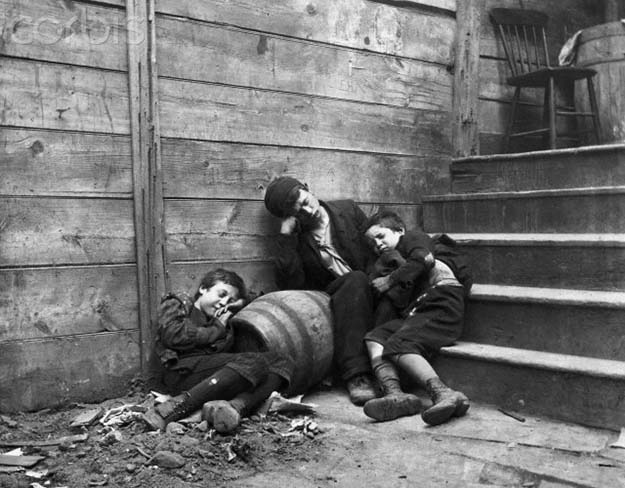 Three homeless boys sleep on a stairway in a Lower East Side alley