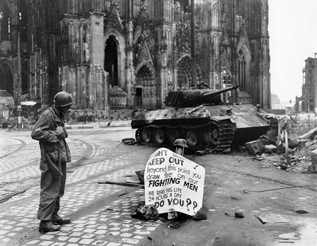 Corporal Luther E. Boger of US 82nd Airborne pision reading a warning sign, Cologne, Germany, 4 April 1945