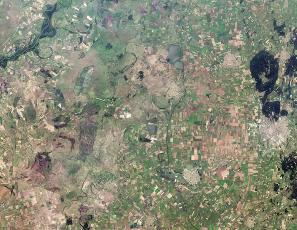 Agricultural fields radiate away from the well-defined outer boundaries of Hungary. The dark areas on the right are dense forests.