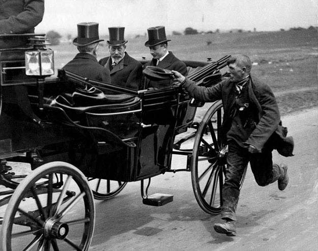 A beggar running alongside King George V’s coach. England, c. 1920