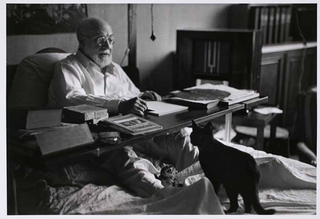 Matisse working in bed, his cats at his feet; Nice, France,1949