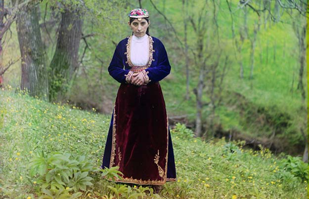 An Armenian woman in national costume poses for Prokudin-Gorskii on a hillside near Artvin (in present day Turkey)