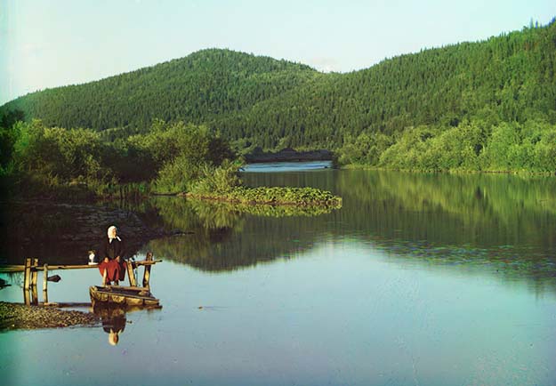 A woman is seated in a calm spot on the Sim River, part of the Volga watershed in 1910.