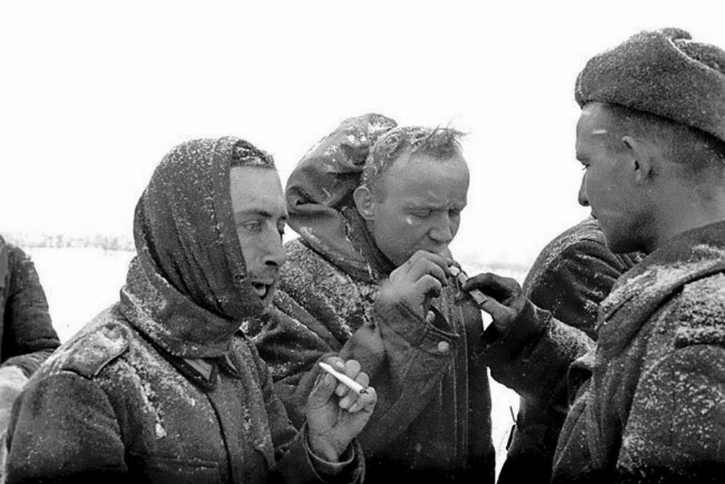 A Soviet soldier gives cigarettes to German POWs captured during the Battle of Stalingrad